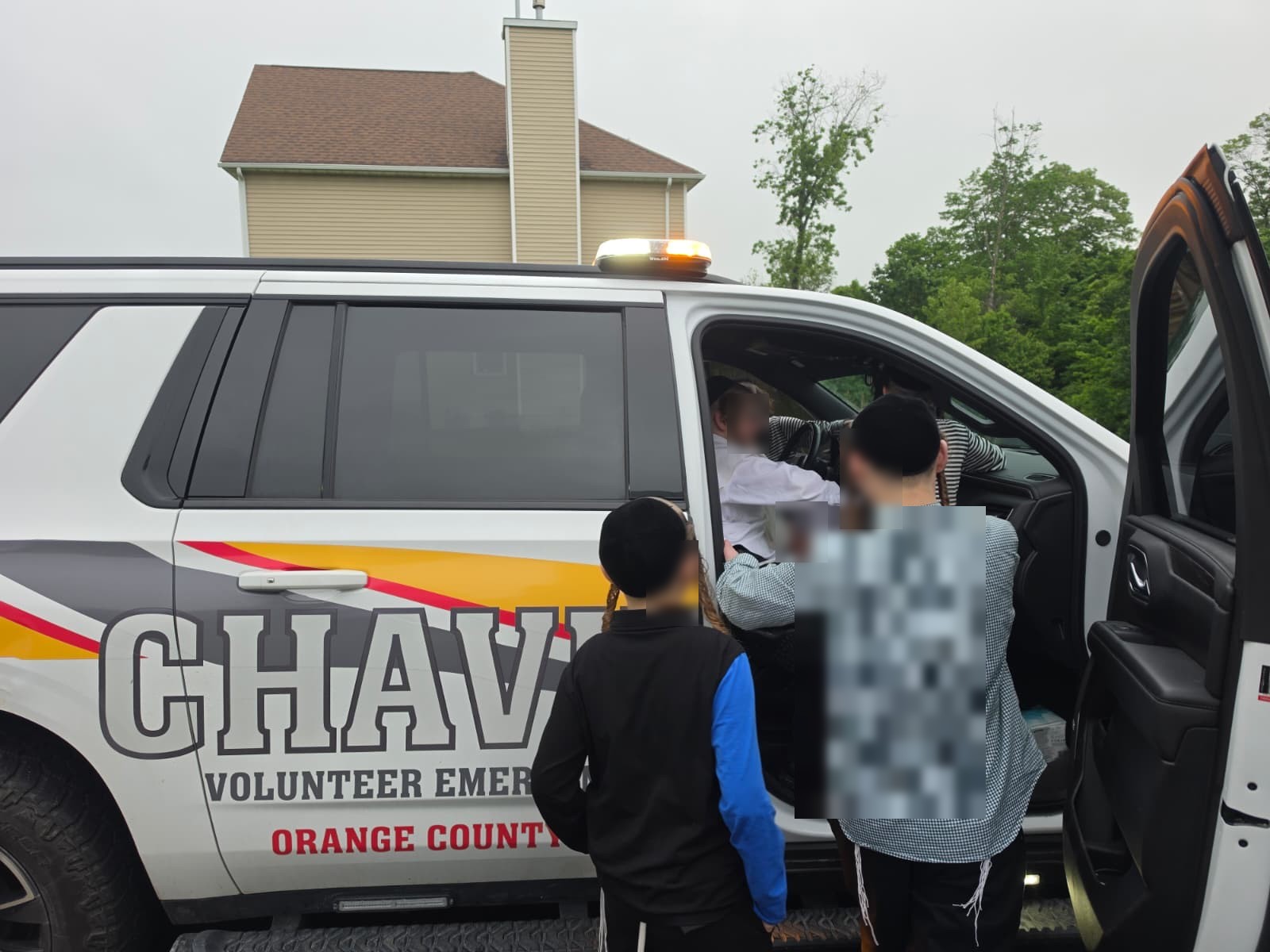 Children looking into the cab of the Orange County Chavivim KJ-501 fly car with a member during the Achyim B'Yachad visit