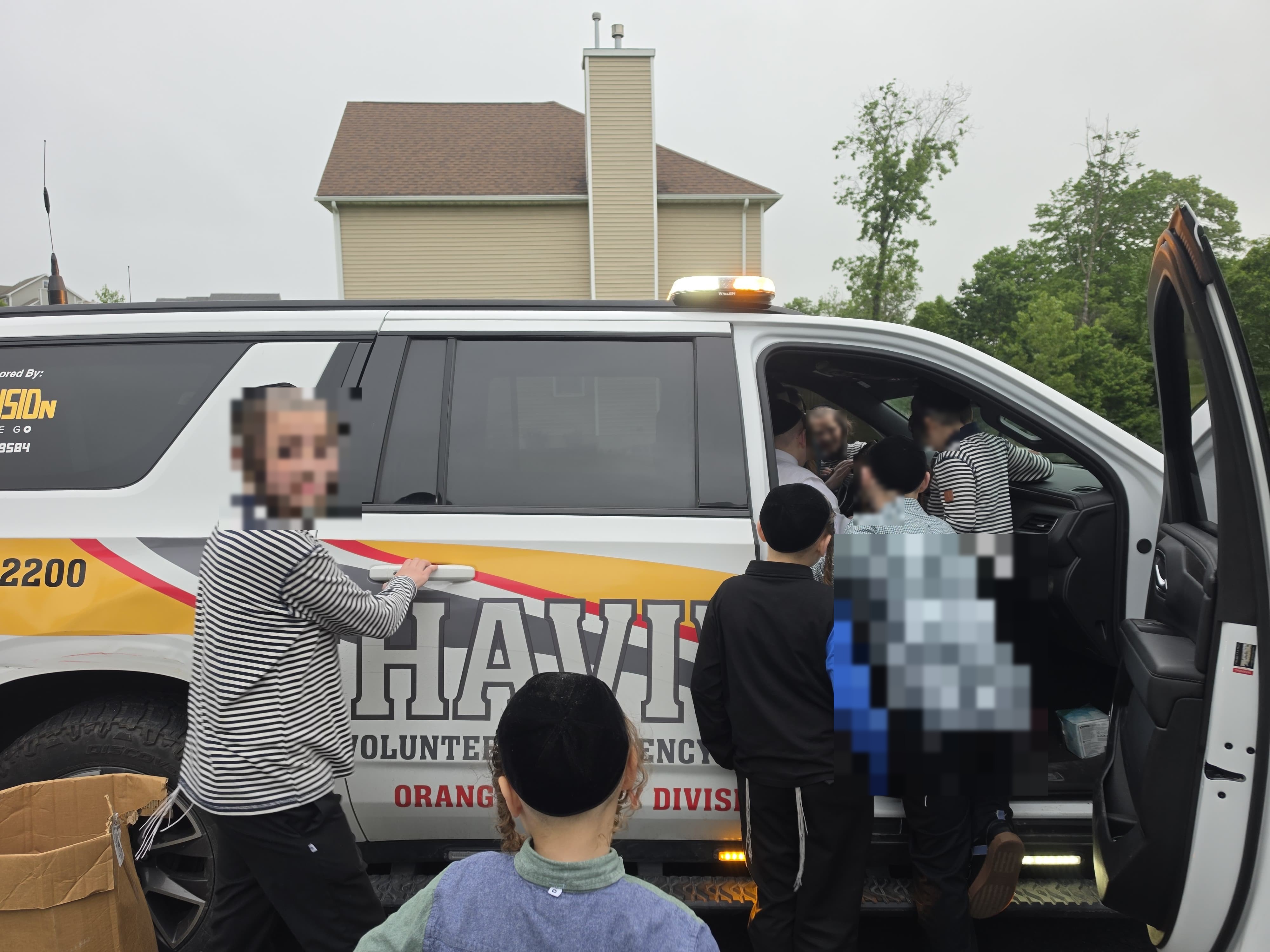 Children from Achyim B'Yachad climbing into the open door of the Orange County Chavivim KJ-501 fly car as a member shows them around the cab