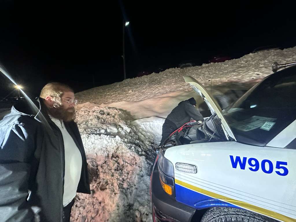 Chavivim member on scene while another works on the engine of Hatzolah ambulance W905 in the background