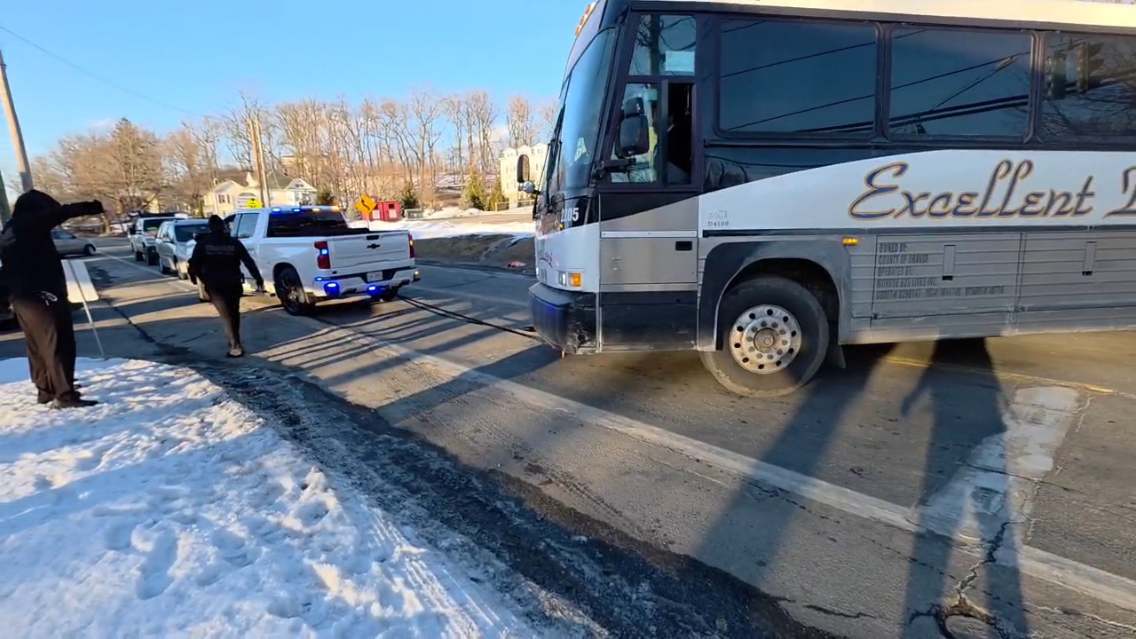 A member's personal truck pulling the Excellent Bus Lines coach free from the intersection with members directing