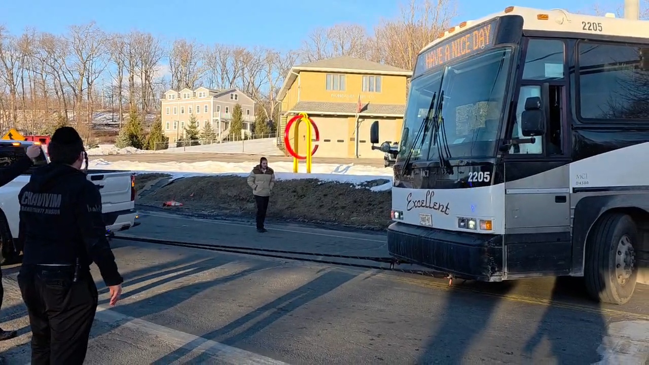 Chavivim member in vest standing at the front of the stuck bus managing the scene at the intersection