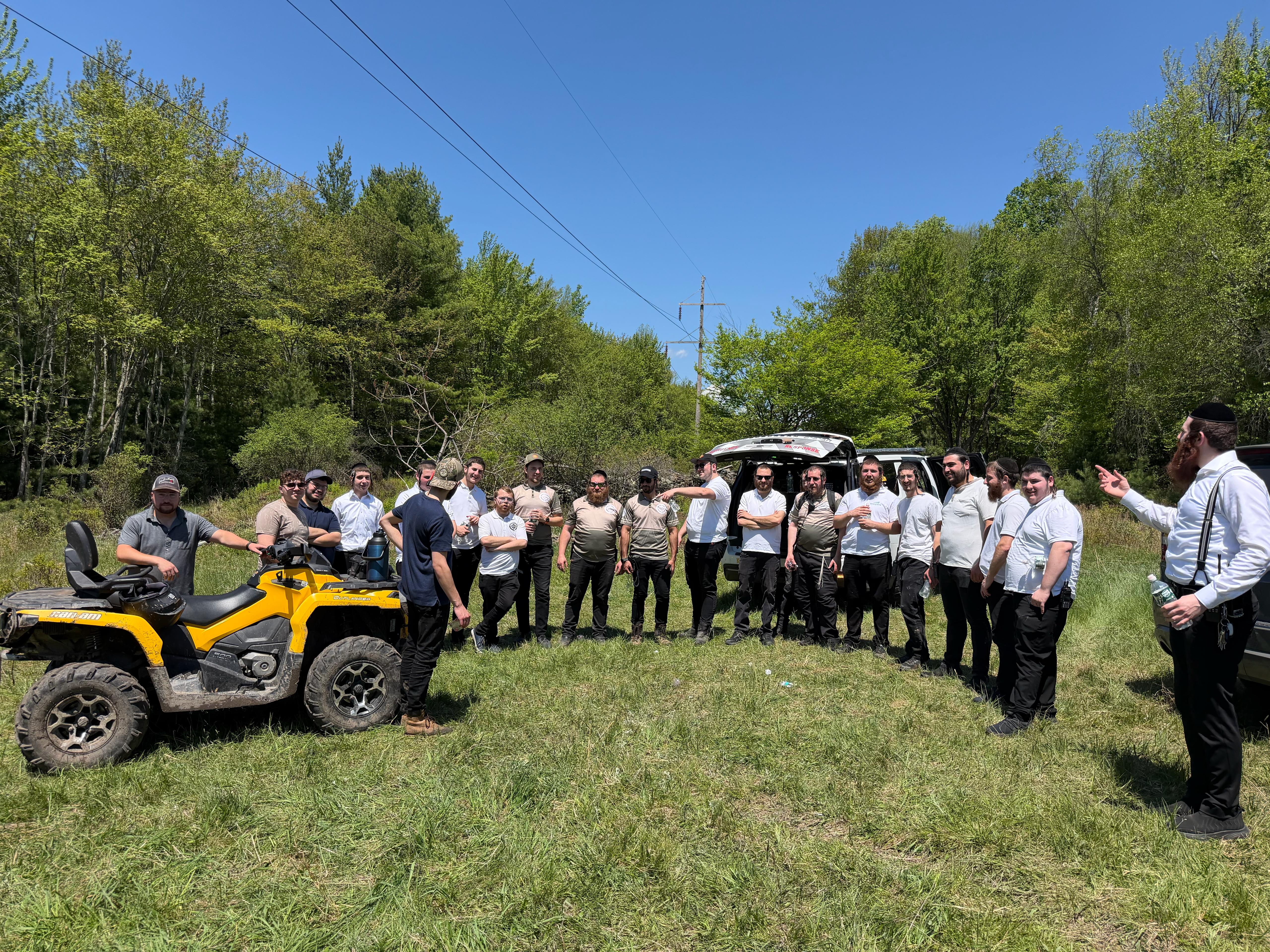 Chavivim SAR training crew gathered in a circle around the SAR ATV at the end of the day in a Catskills clearing