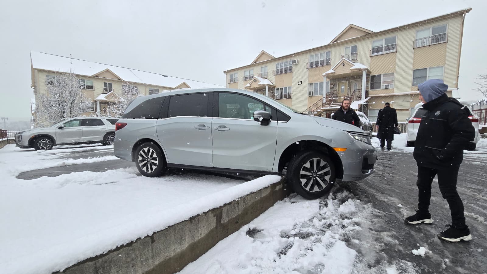 Honda Odyssey minivan high-centered on a curb in the snow with Chavivim members on scene