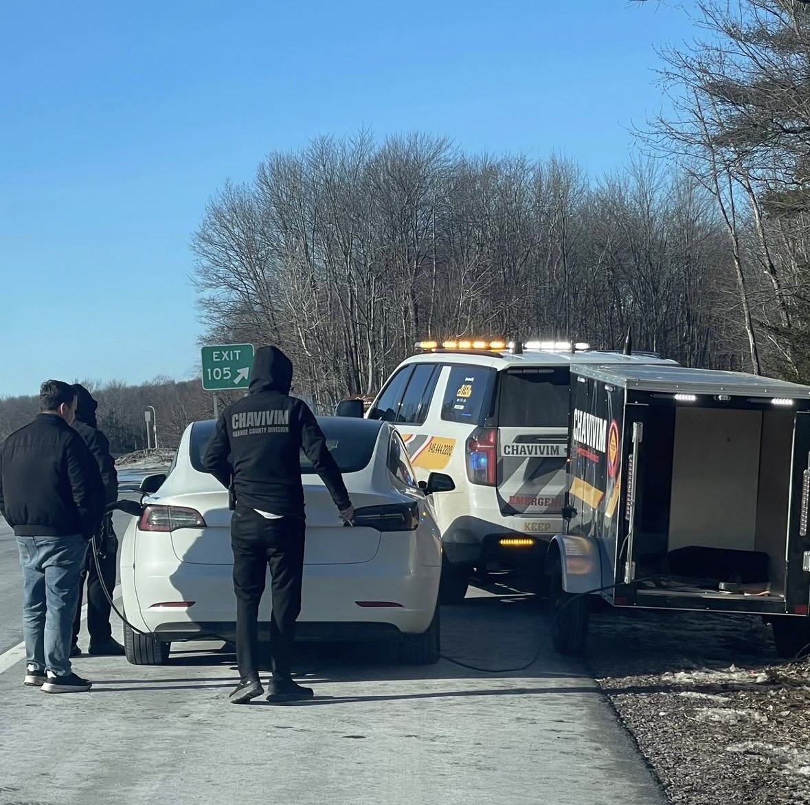 Chavivim members standing with a stranded Tesla on the shoulder of Route 17 at Exit 105 with the Chavivim response truck behind them