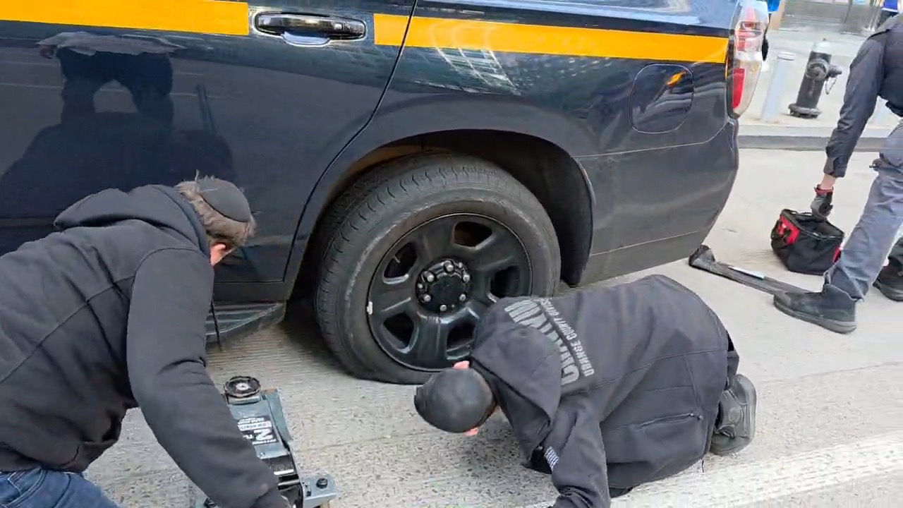 Close-up of Chavivim members removing the blown tire from the rear axle of the NYSP SUV