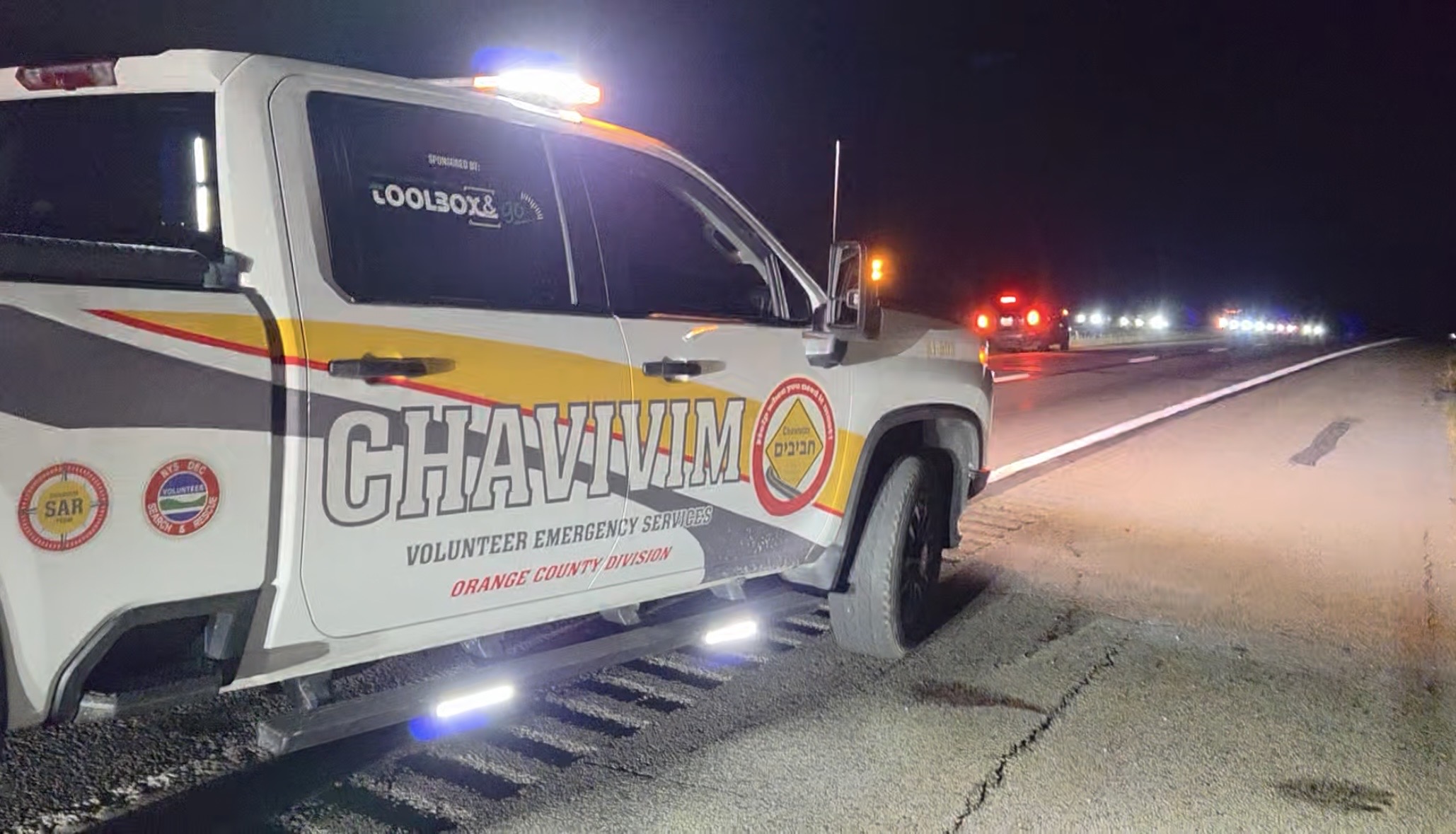 Orange County Chavivim recovery truck on the shoulder of Route 17 at night with NY State Police vehicles in the distance