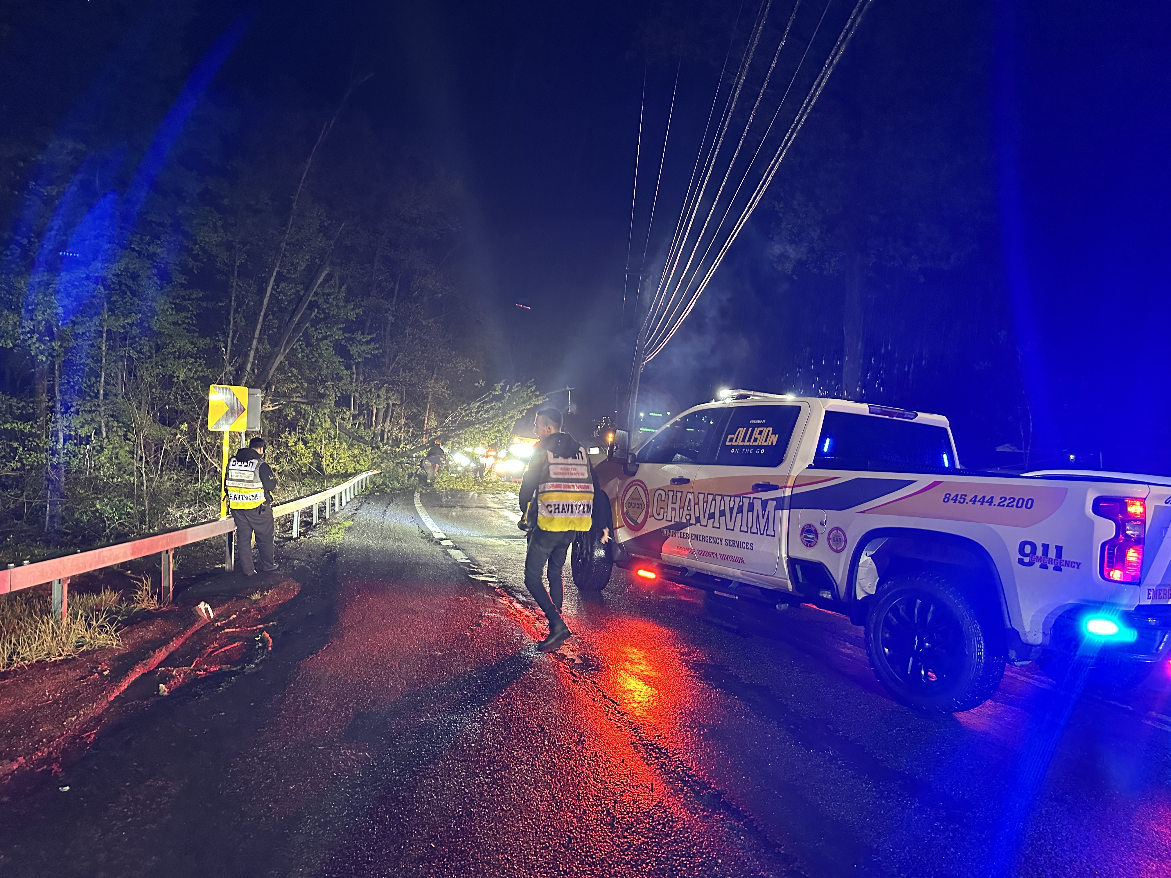 Trees down across Route 208 with members staging the scene at night