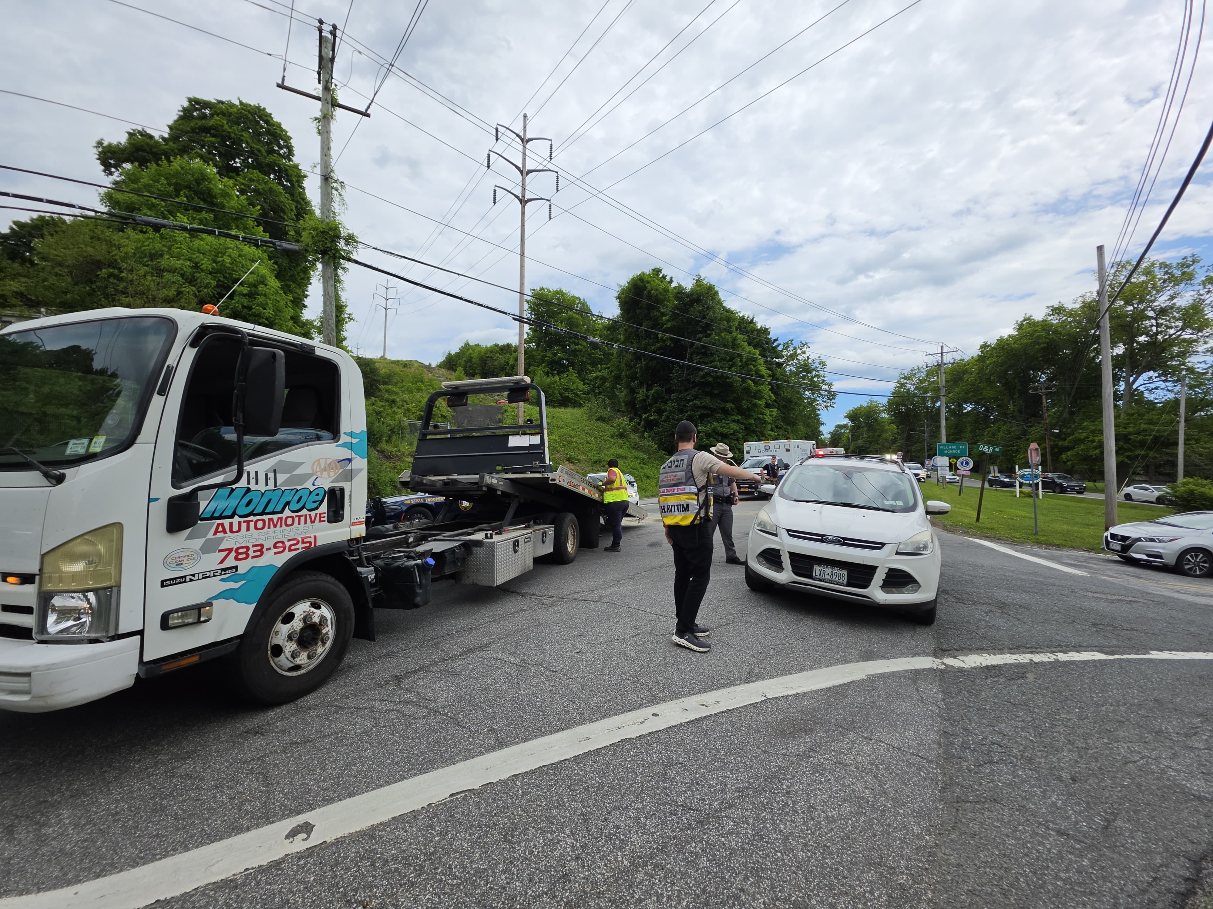 The Monroe Automotive flatbed pulling away from the intersection as a Chavivim member keeps traffic moving and the scene clears