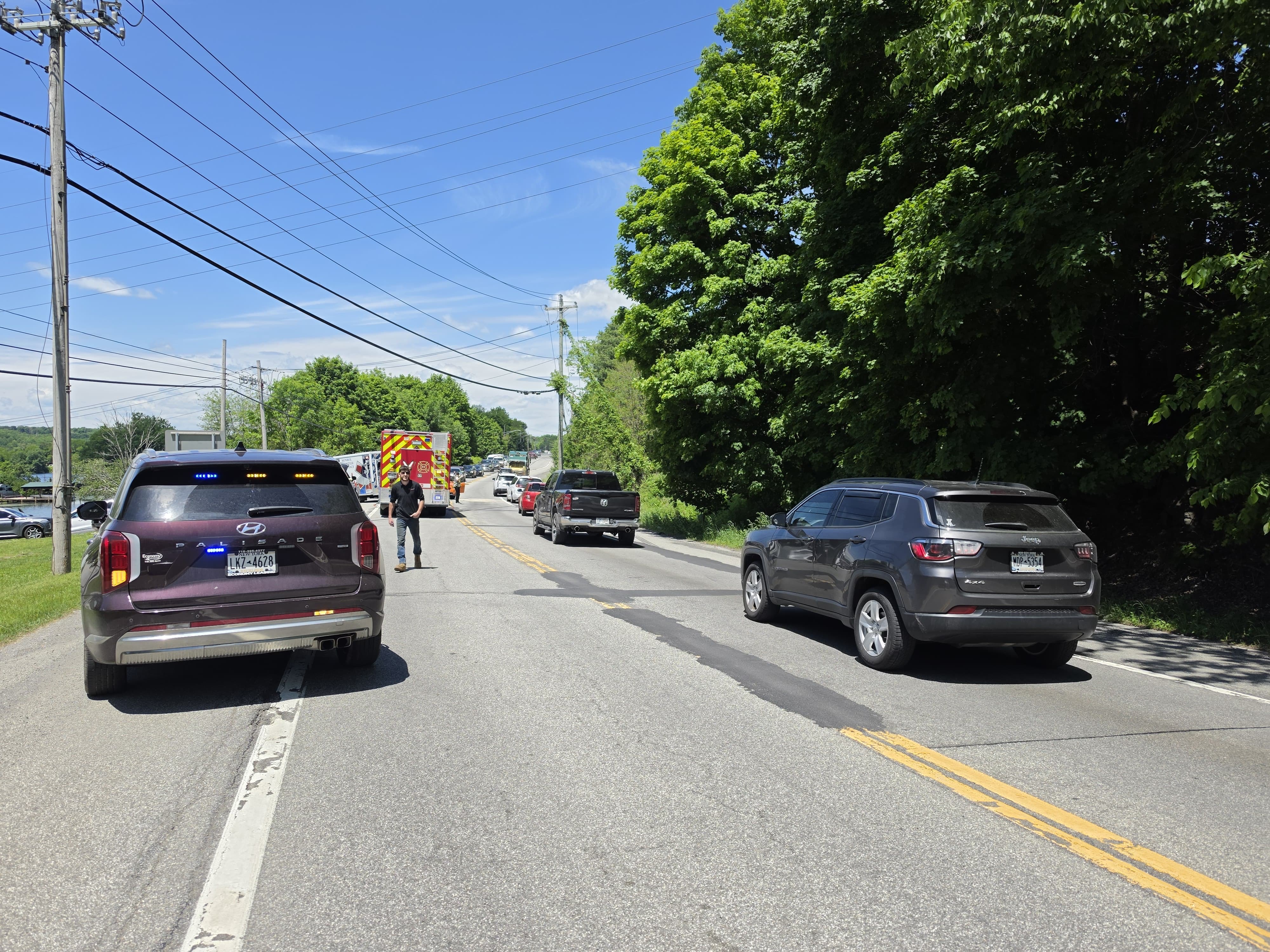 Traffic stopped in both directions along NY-208 with a fire engine and ambulance staged in the distance while crews work the crash scene