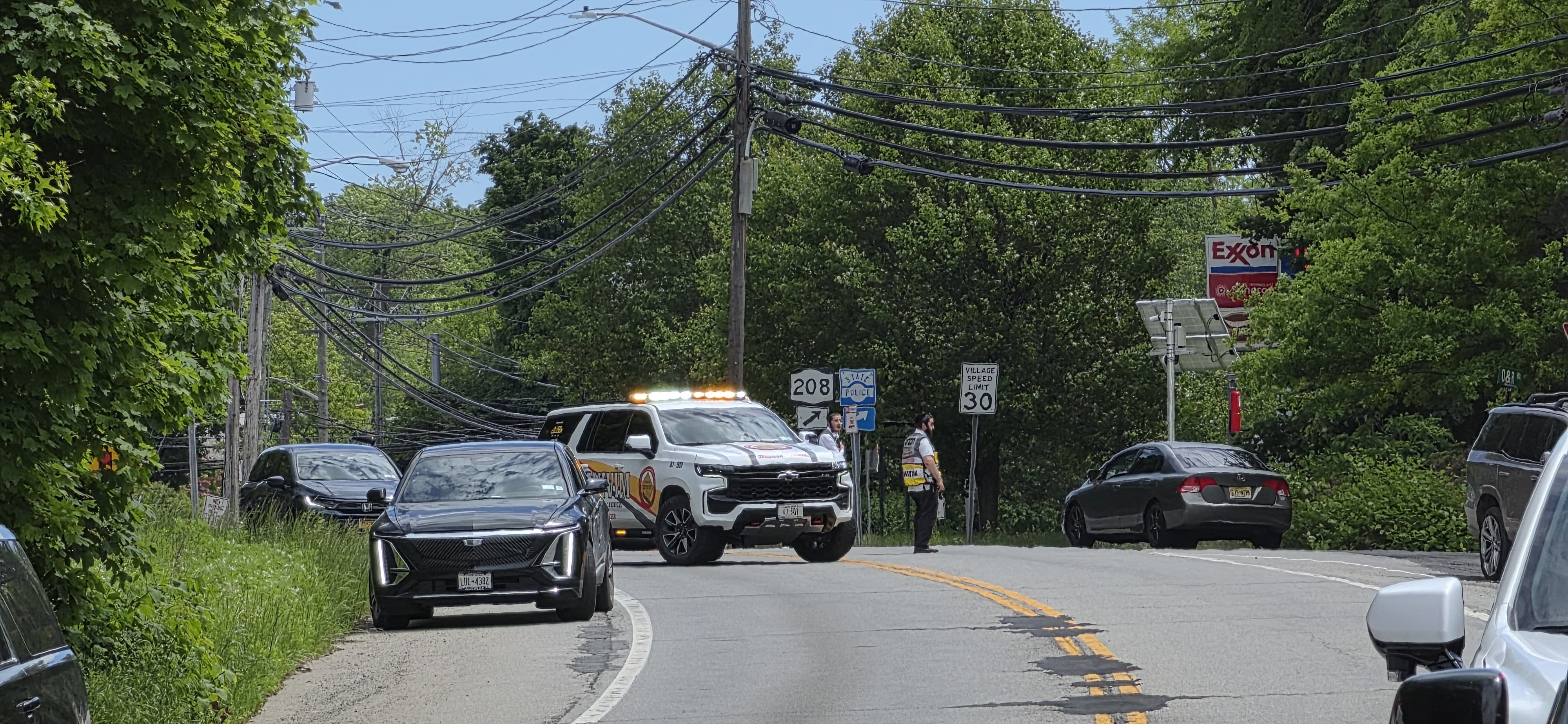 A wide shot of NY-208 with a Chavivim member directing traffic and vehicles held back during the second crash