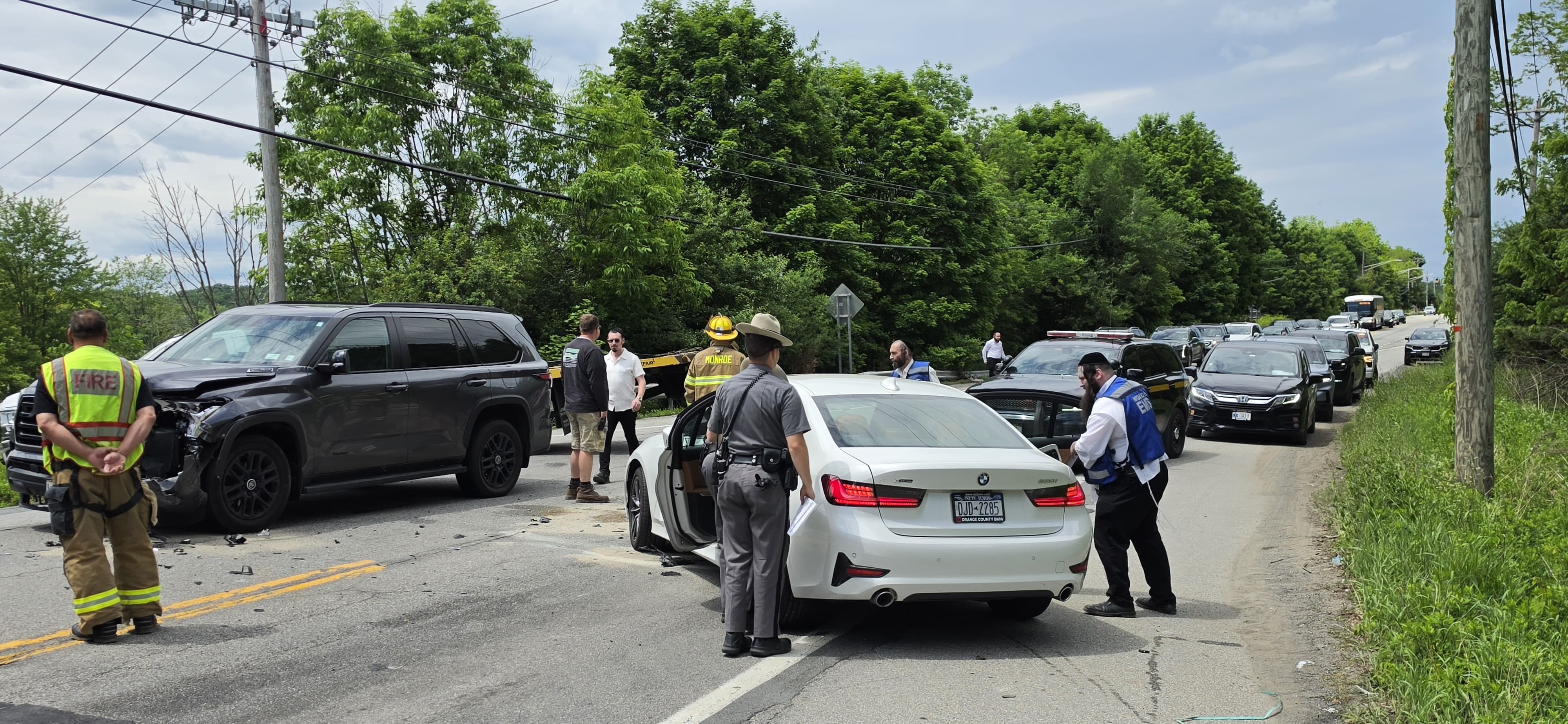 Firefighters, Chavivim members, and bystanders gathered around the damaged black SUV and white sedan at the second crash